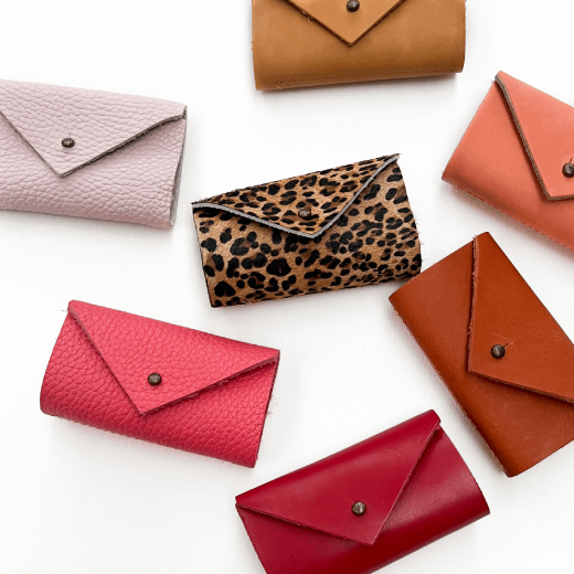 A group of seven needle cases of various colours are displayed on a white top.